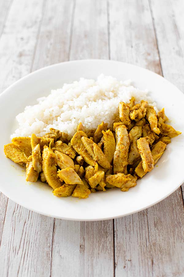 shawarma on a white plate with white rice on a white wooden table