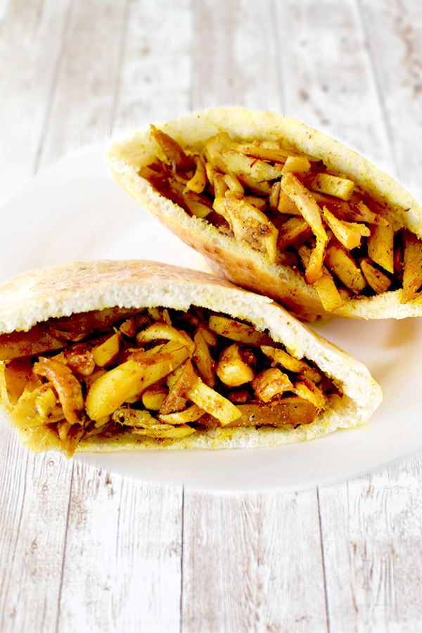 Easy Homemade Turkey Shawarma in two pita halves on a white plate on a white wood table