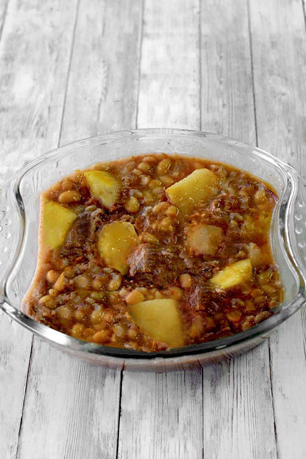 cholent in a clear bowl on a wide plank board background