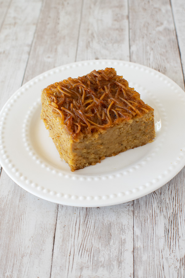 A square of Jerusalem kugel on a white plate on a white wood background