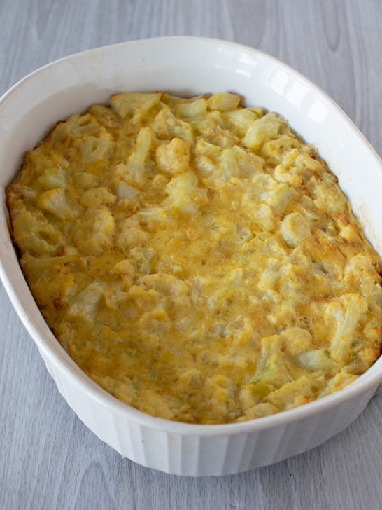 Cauliflower kugel in a white deep oval serving dish on a white wood background
