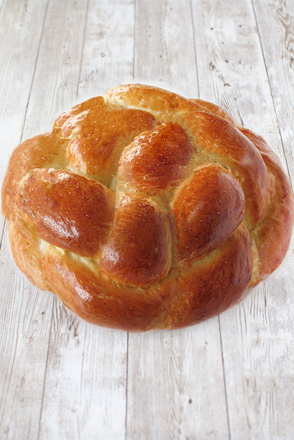 Round fluffy challah bread  on a white wood table