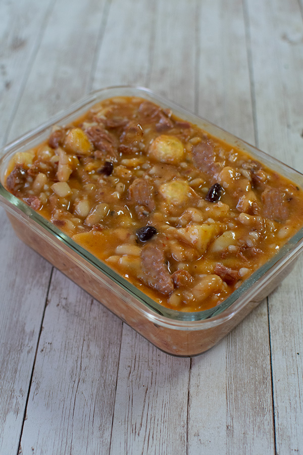Cholent in a clear rectangular dish on a white wood table