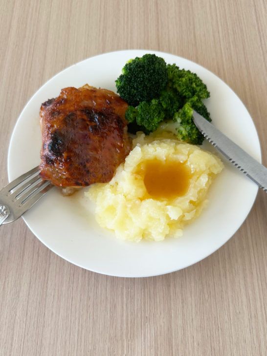 Duck sauce chicken on a white plate with broccoli and mashed potatoes and gravy