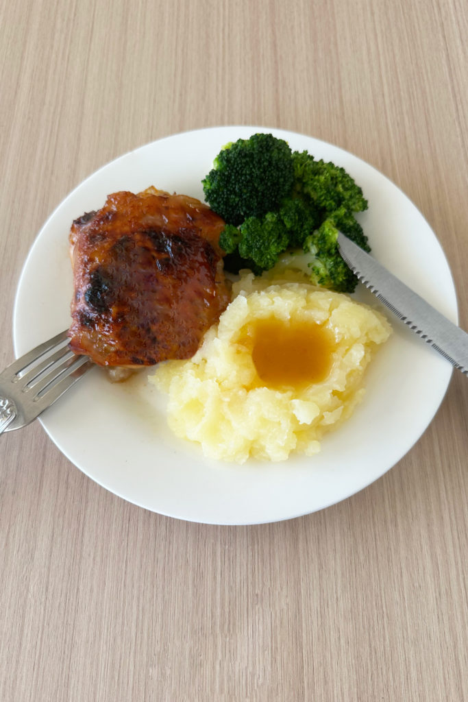 Duck sauce chicken on a white plate with broccoli and mashed potatoes and gravy