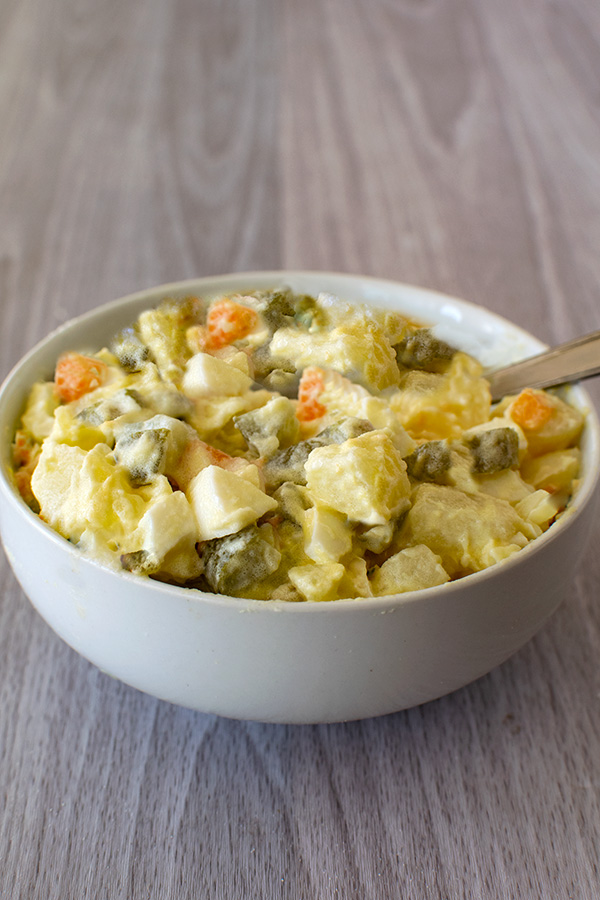 Oliver salad in a white bowl on a white wood table.