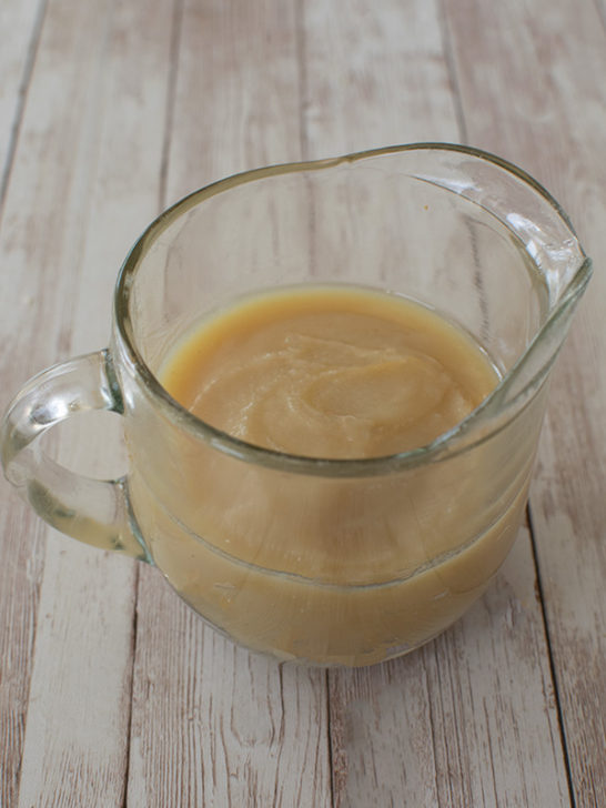 Chicken Schmaltz in a clear gravy cup on a white slatted wood table