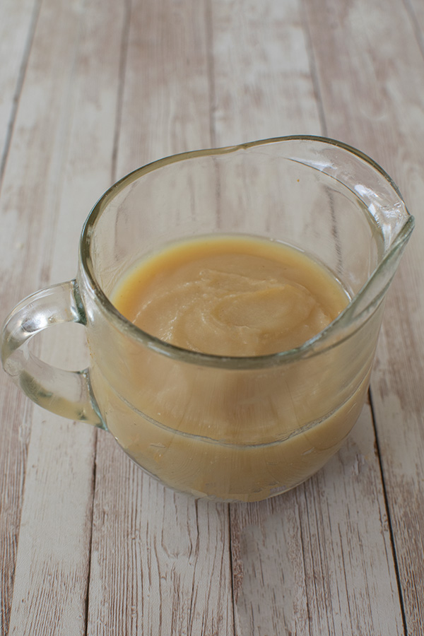 Chicken Schmaltz in a clear gravy cup on a white slatted wood table