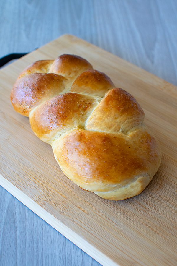 Fluffy Water Challah on a bread board on a white wood table