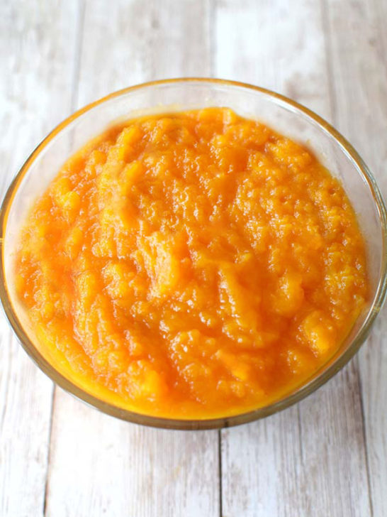 Butternut squash puree in a clear bowl on a white wood background