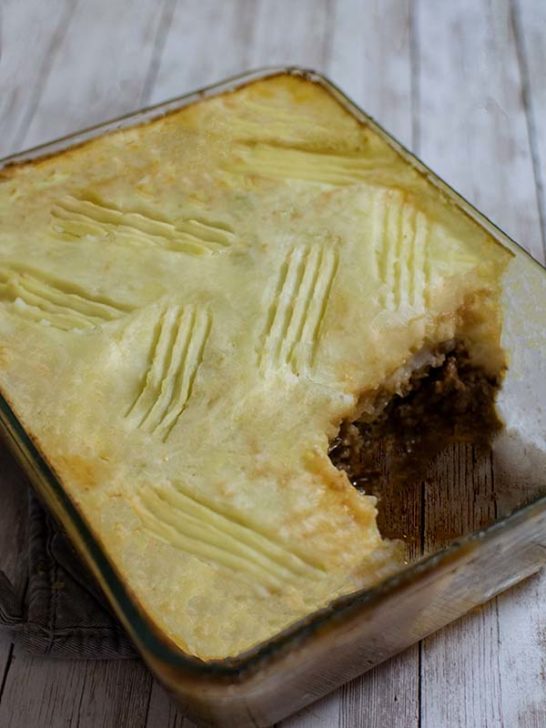 Shepherd's Pie (cottage pie) in a clear glass rectangular casserole dish on a white wood table