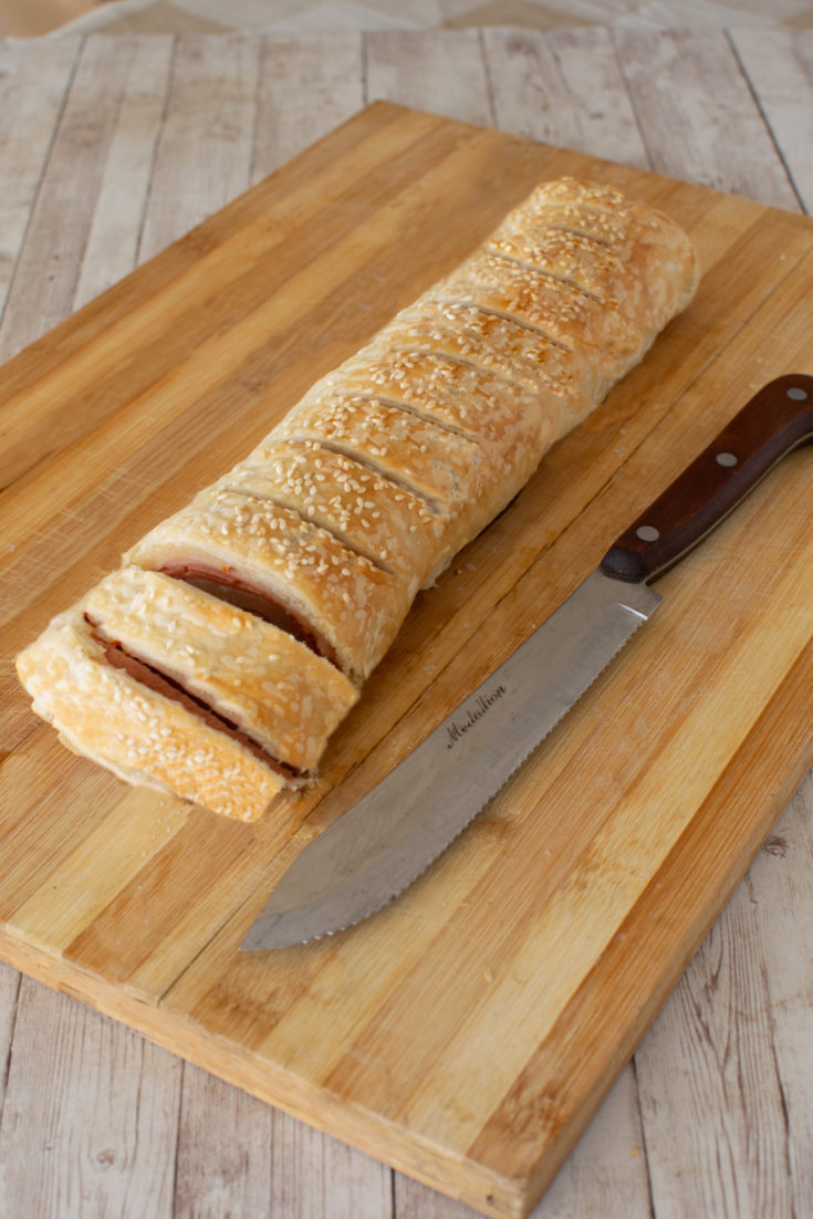 Deli roll on a bread board, sliced