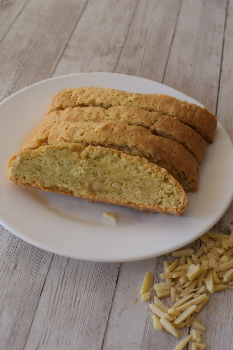 Easy Dairy-Free Mandel Bread with almond slices on a white plate on a white wood table with almond slices nearby