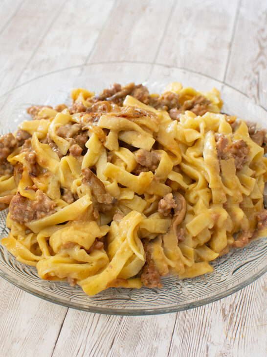 Ground beef stroganoff in a clear bowl on a white wood table