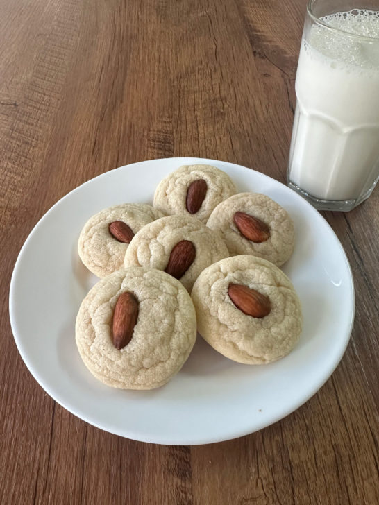 Easy Almond Flavored Cookes on a white plate on a dark wood table with a glass nearby