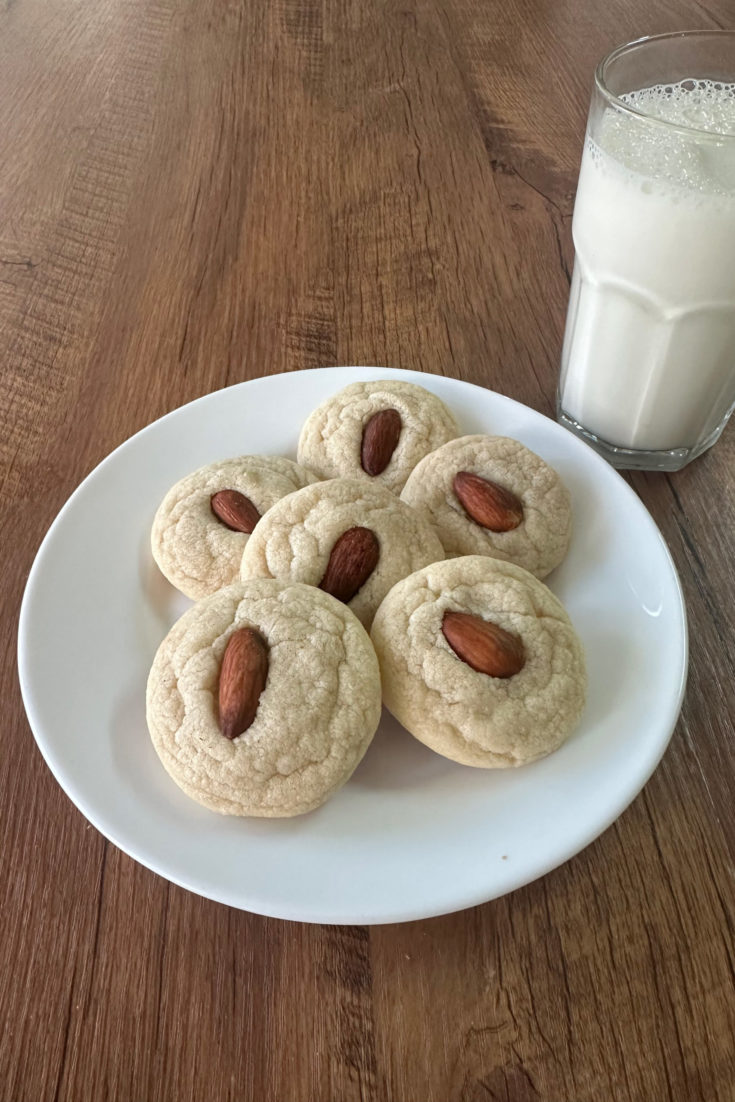 Easy Almond Flavored Cookes on a white plate on a dark wood table with a glass nearby