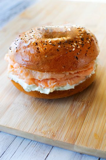 Everything bagel with lox and cream cheese on a wooden cutting board