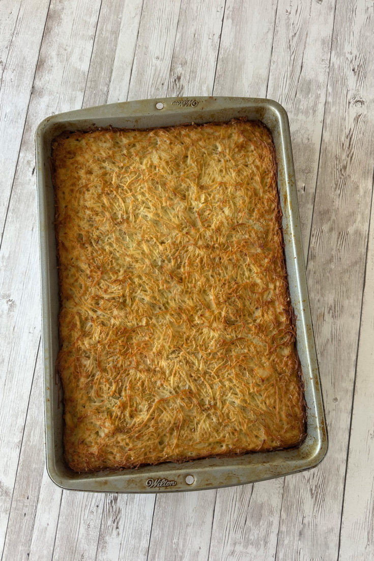 potato kugel for passover in a pan on a white wood table