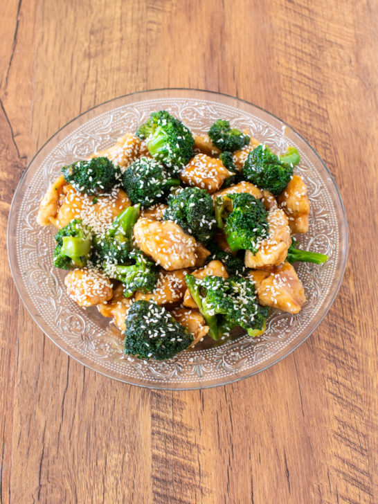 Honey Garlic chicken with broccoli in a clear serving bowl on a dark wood table