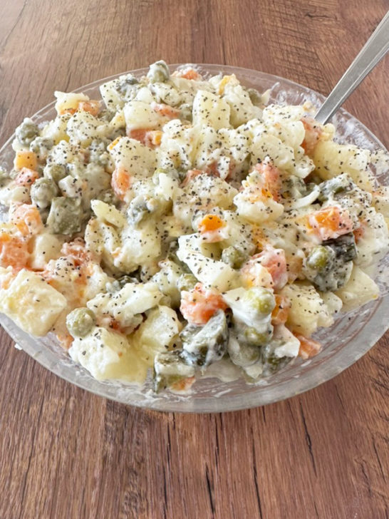 Israeli Potato salad in a clear bowl on a dark wood table