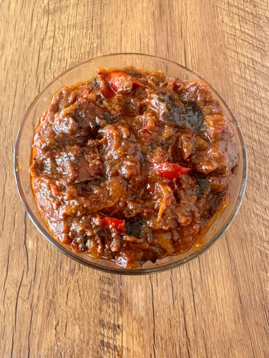 Moroccan-Israeli eggplant salad in a clear glass bowl on a dark wood table