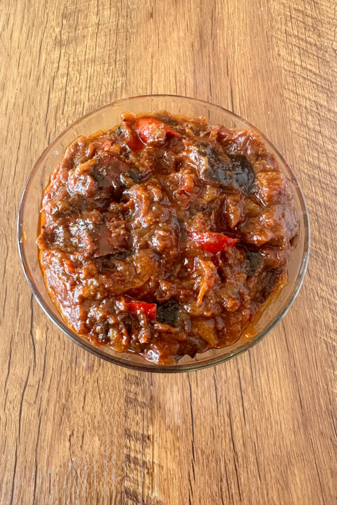 Moroccan-Israeli eggplant salad in a clear glass bowl on a dark wood table