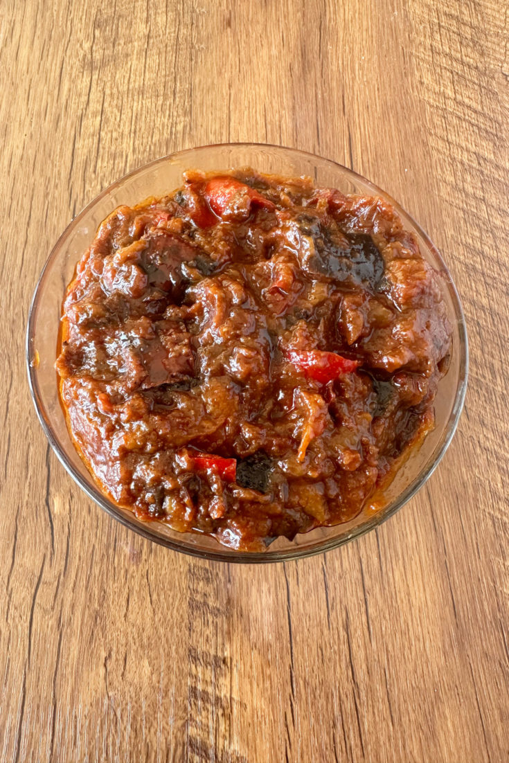 Moroccan-Israeli eggplant salad in a clear glass bowl on a dark wood table