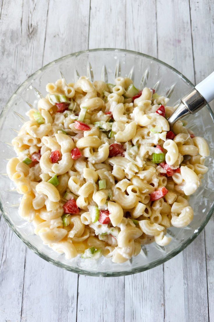 Deli-style macaroni salad in a clear bowl on a light wood table