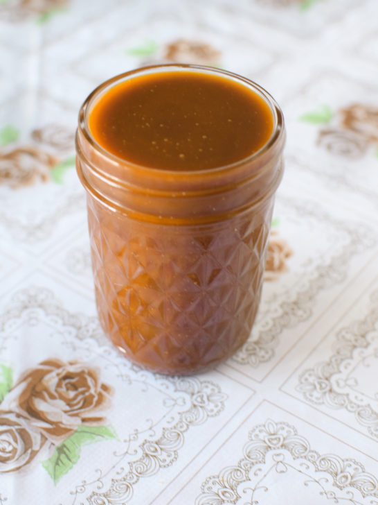 Dairy-free caramel sauce in a glass jar on a flowered background
