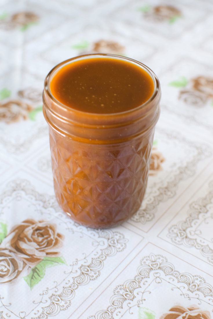 Dairy-free caramel sauce in a glass jar on a flowered background