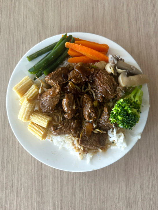 Easy Kosher Beef Chop Suey with vegetables around on a white plate on a light wood table.