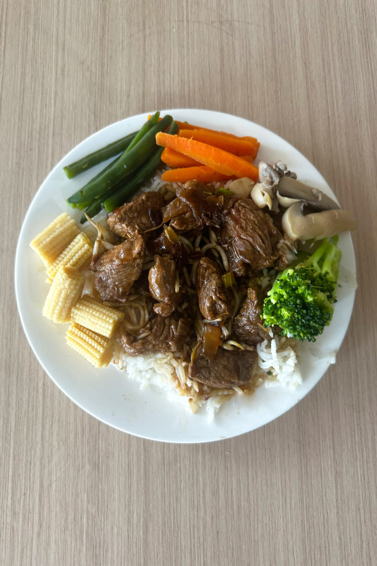 Easy Kosher Beef Chop Suey with vegetables around on a white plate on a light wood table.