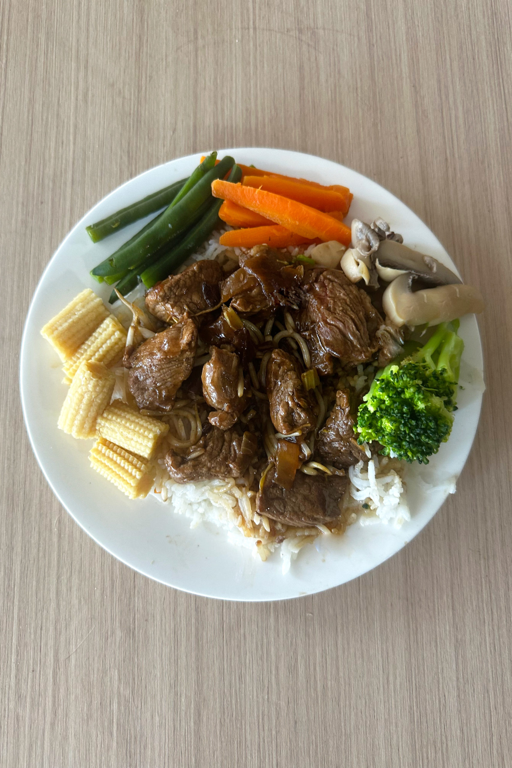 Easy Kosher Beef Chop Suey with vegetables around on a white plate on a light wood table.