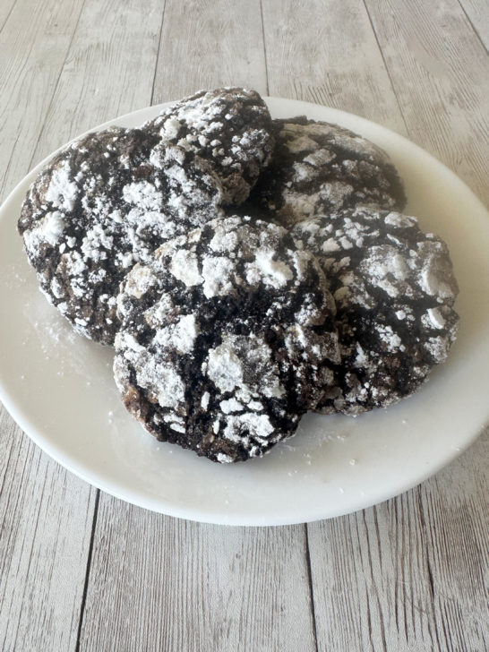 dairy-free chocolate crinkle cookies on a white plate on a white wood table