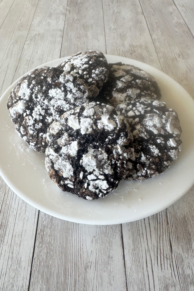 dairy-free chocolate crinkle cookies on a white plate on a white wood table