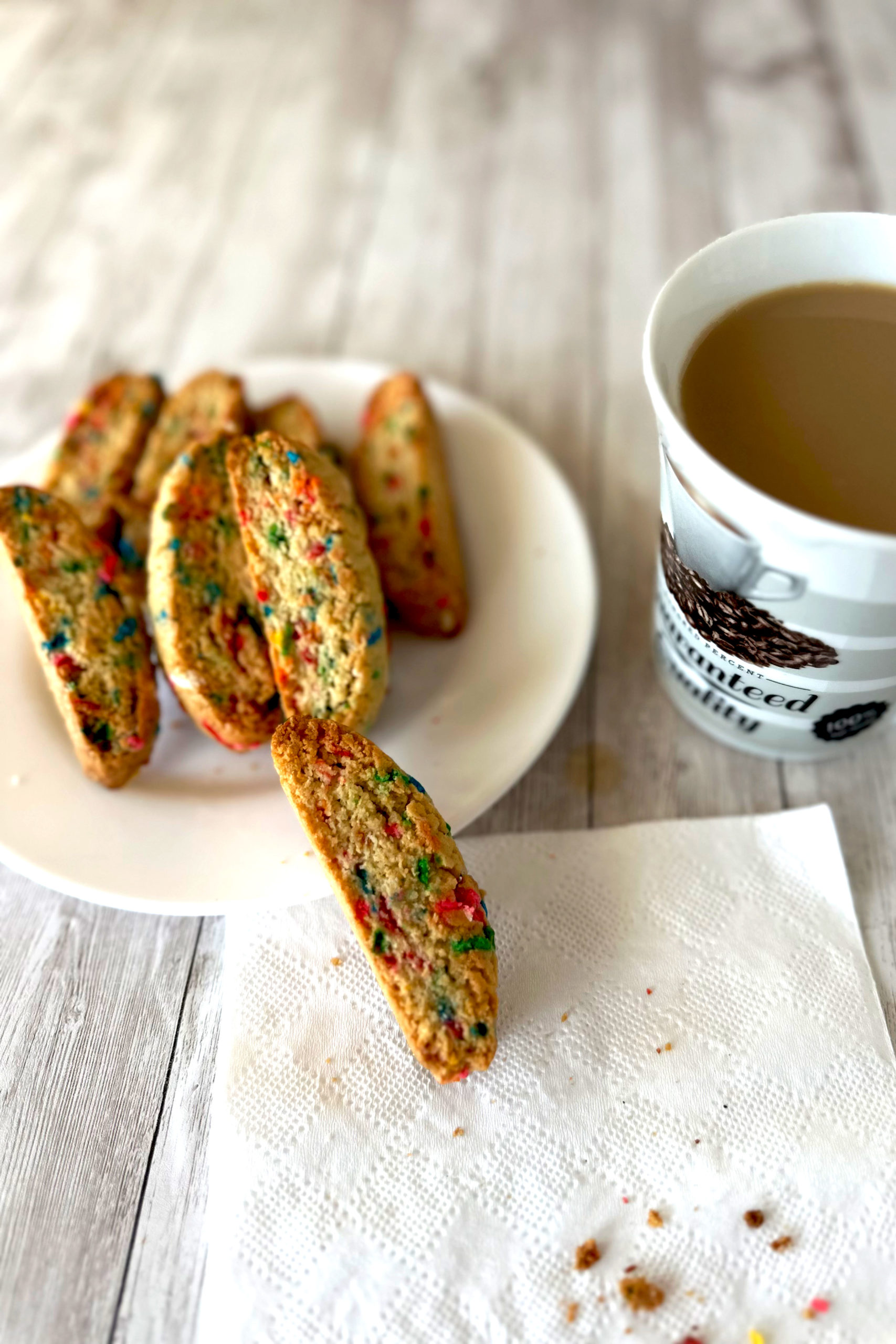 Funfetti bars on a plate near a cup of coffee on a white wood table