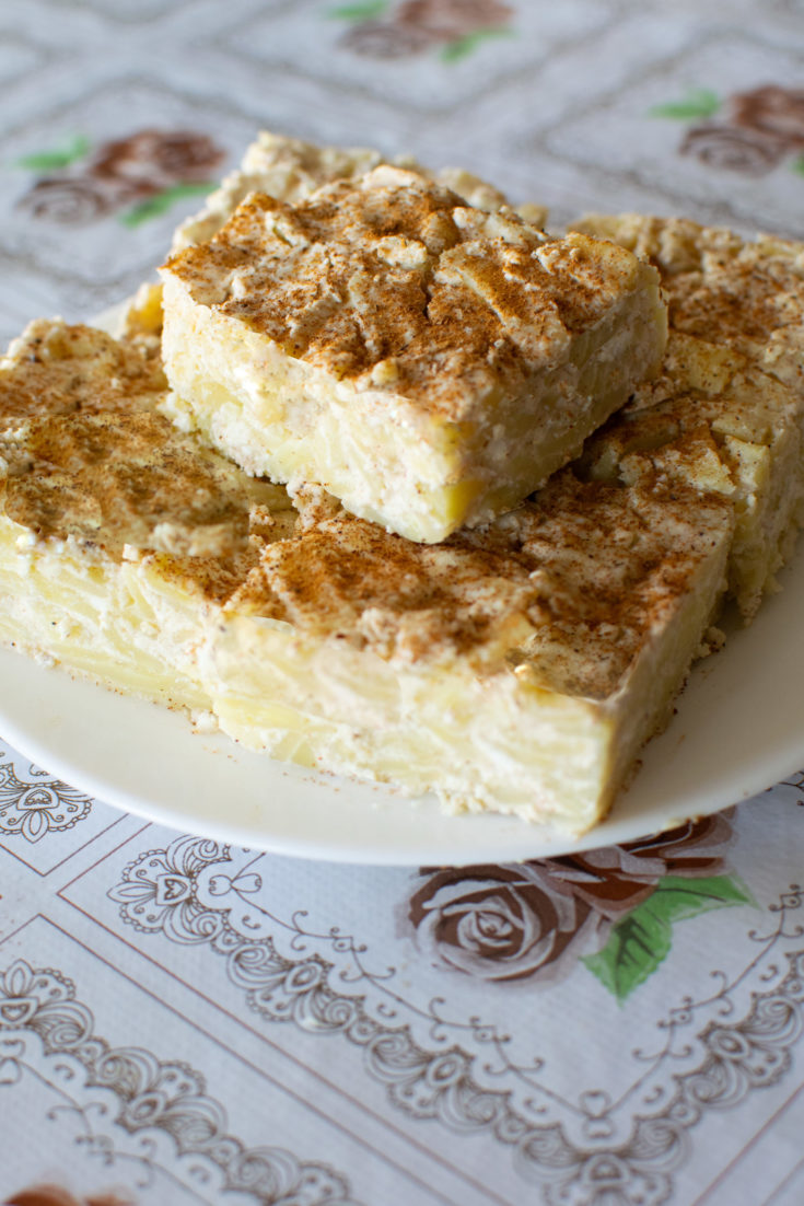 pieces of lokshen kugel on a white plate on a flowered tablecloth